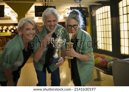 Portrait smiling bowling team holding trophies bowling alley