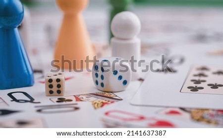Colourful picture of two dice cubes with pawns and solitaire cards on the ground.