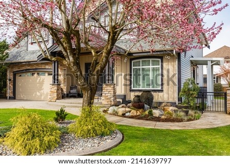 Neighborhood modern houses building with spring flowers in patio in BC, Canada. Canadian modern residential architecture. Nobody, street photo