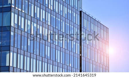 Glass building with transparent facade of the building and blue sky. Structural glass wall reflecting blue sky. Abstract modern architecture fragment. Contemporary architectural background. Royalty-Free Stock Photo #2141645319