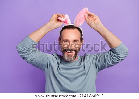 Photo of satisfied friendly man hands touch bunny ears beaming smile isolated on violet color background