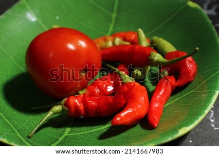 red cloves and tomatoes to make sambal (chili sauce) in a green container