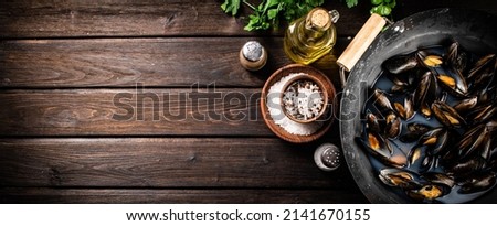 Mussels in a saucepan with parsley and spices. On a wooden background. High quality photo Royalty-Free Stock Photo #2141670155