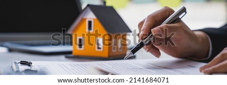 Real estate agent working sign agreement document contract for home loan insurance approving purchases for client with house model and key on table Royalty-Free Stock Photo #2141684071