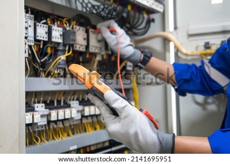 Electricity and electrical maintenance service, Engineer using measuring equipment tool checking electric current voltage at circuit breaker terminal and cable wiring main power distribution board. Royalty-Free Stock Photo #2141695951