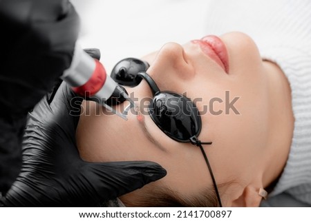 Laser removal of permanent makeup eyebrow correction of young woman in salon. Royalty-Free Stock Photo #2141700897