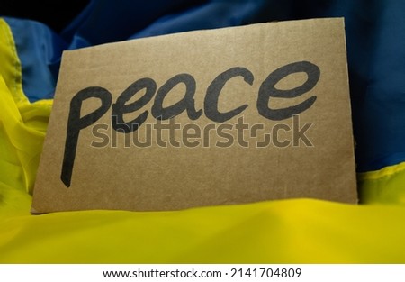 Ukrainian flag and "Peace" placard sign in protest manifestation against Russia invasion and war on Ukraine. Russian attack, anti-war demonstration.