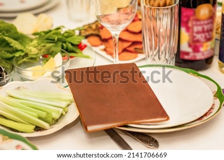 Table with Passover Haggadah and traditional food. Seder Plate and Passover Haggadah Prepare to Pesach Seder. Royalty-Free Stock Photo #2141706669