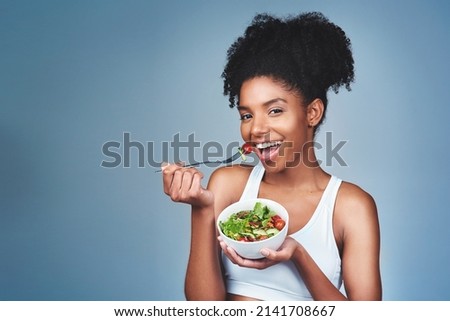 I like to enjoy my food guilt-free. Studio shot of an attractive young woman eating salad against a grey background. Royalty-Free Stock Photo #2141708667