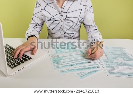 business woman filling out 1040 tax form using laptop and calculator