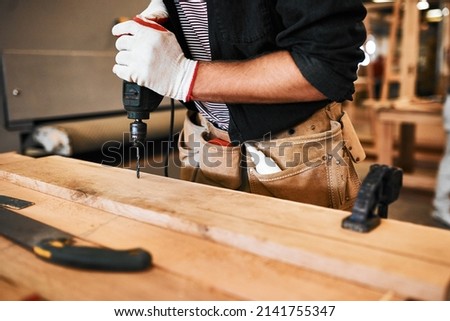 Its all apart of the drill. Cropped shot of an unrecognizable carpenter using an electric drill inside a workshop. Royalty-Free Stock Photo #2141755347