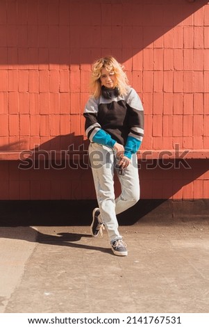 Young blonde creator posing over brick wall and holding her vintage analog camera. Vertical shot. High quality photo