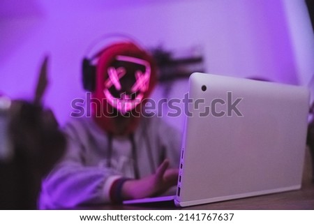 Dangerous masked hacker using laptop. Internet security concept. High quality photo