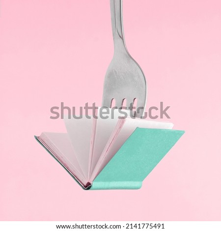 Fork and green book on isolated pastel pink background. The idea of book fair, reading, promotions or education. Poster, wallpaper or gift card. Literary idea. Minimal abstract art concept.