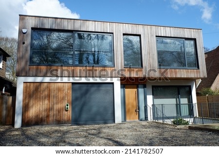 Modern two storey flat roofed house, clad with external cedar wood Royalty-Free Stock Photo #2141782507