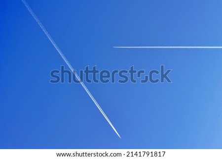 Two Airplanes on the blue sky with long white contrails.  Royalty-Free Stock Photo #2141791817