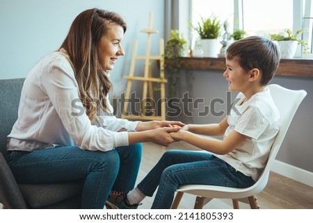 Shot of a little boy talking to a psychologist. Attentive and sympathetic woman psychologist listens to little boy. Notes to himself in clipboard. Mental health. Royalty-Free Stock Photo #2141805393