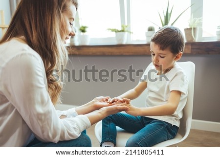 Young boy having therapy with a child psychologist. Smiling woman talking to boy. Friendly young child psychologist talking with little boy suffering from emotional disorder in bright office Royalty-Free Stock Photo #2141805411