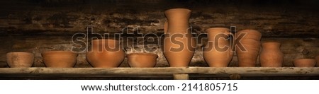 earthenware stands in a row on a rough plank shelf against a log wall. large-format still life in a simple rustic style. pottery shop