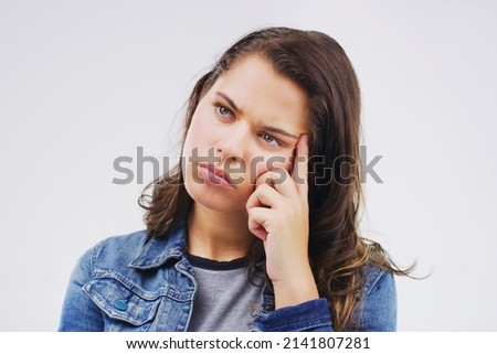Your head can be your worst enemy. Studio shot of a young woman looking thoughtful against a gray background. Royalty-Free Stock Photo #2141807281