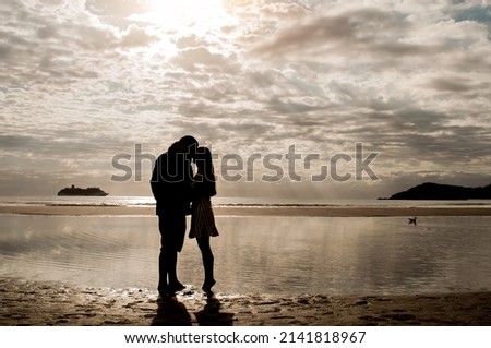 Silhouette of couple in love on the beach at sunrise.