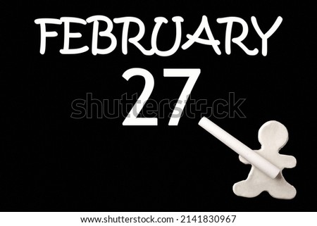 27th day of February. A small white plasticine man writing the date 27 February on a black board. Business concept. Education concept. Winter month, day of the year concept.