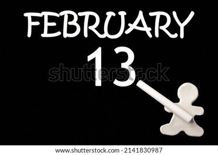 13th day of February. A small white plasticine man writing the date 13 February on a black board. Business concept. Education concept. Winter month, day of the year concept.