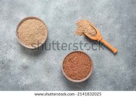 Flax flour. Flaxseed flour in a bowl on a gray concrete grunge background. Top view, flat lay. Textured object, selective focus