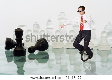 Businessman keeping his balance riding a mono cycle on a chess board