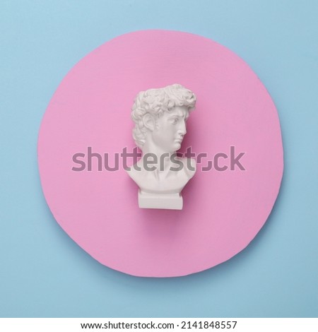 David bust on a blue background with a pink circle. Minimal still life