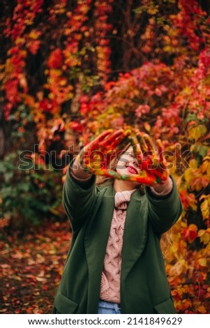 Happy woman with palms in colorful paint outdoor in autumn park