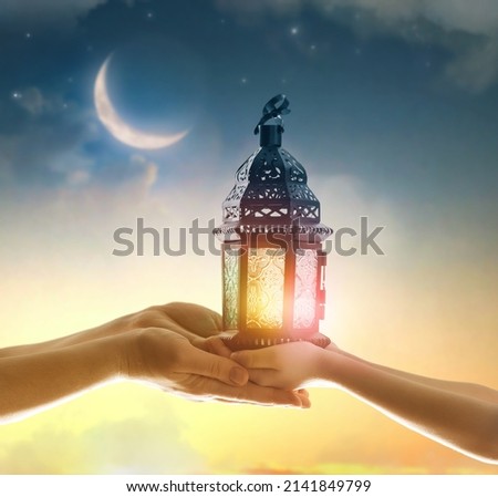 Ornamental Arabic lantern with burning candle glowing in hand. Festive greeting card, invitation for Muslim holy month Ramadan Kareem. Royalty-Free Stock Photo #2141849799