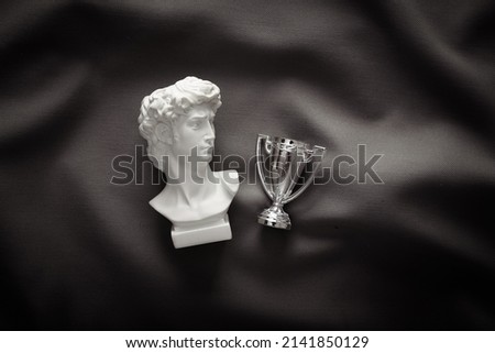 David plaster bust with winner cup on gray crumpled silk background