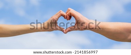 Female and man hands in the form of heart against the sky. Hands in shape of love heart. Heart from hands on a sky background. Love, friendship concept. Girl and male hand in heart form love blue sky. Royalty-Free Stock Photo #2141856997