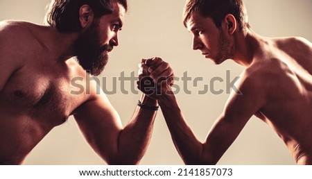 Arms wrestling thin hand, big strong arm in studio. Two man's hands clasped arm wrestling, strong and weak, unequal match. Arm wrestling.