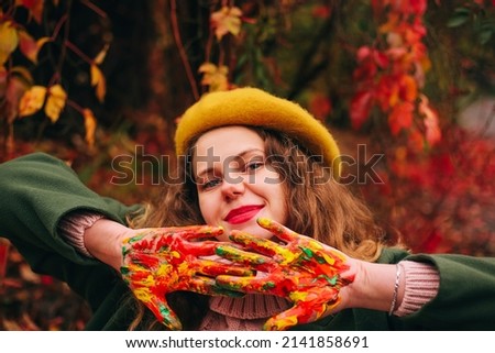 Woman in yellow beret with palms in paint outdoor autumn