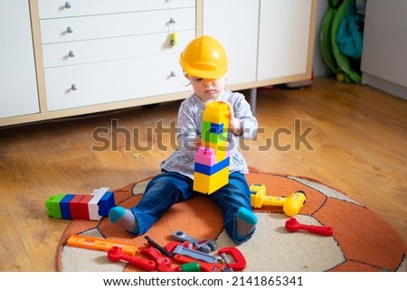 Baby girl builds a tower of  cubes. Child playing with  cubes on the floor
