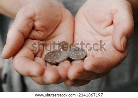 Coins in female wrinkled hands, senior caucasian woman holding money in palms close-up. Concept of poverty, bankruptcy, financial and economic crisis, pension. Macro photo, selective focus.