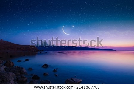 Ramadan religious background with bright crescent, stars and mosque reflected in serene sea. Month of Ramadan is that in which was revealed Quran. Mixed media image. Royalty-Free Stock Photo #2141869707