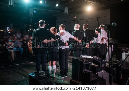 Loud applause for actors. Large group of artists bow to audience on stage in theatre. Obeisance to the spectators who applaud and give great support to the actors. Back view Royalty-Free Stock Photo #2141871077