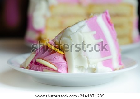 Moist madeira sponge, layered with plum and raspberry jam, coated and topped with white and pink colour frostings, decorated with white chocolate decorations, birthday cake