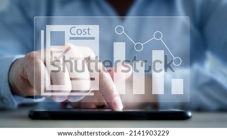 Cost reduction Concept. Businessman with his hand lowers the arrow of the graph. Cost text with a down arrow.budget,Cost Management. cut.  Royalty-Free Stock Photo #2141903229