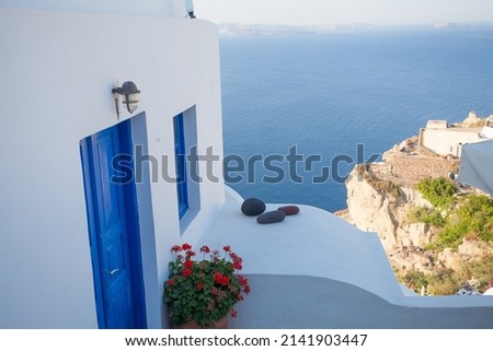 Old blue door and red flowers, traditional Greek architecture, Santorini island. Beautiful details of Santorini, white houses, blue doors and shutters, the Aegean Sea, Greece.