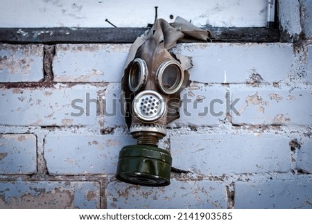 Old gas mask with coal filter hung on the brick wall. Concept - Nuclear Disarmament and Radiation Protection, epidemic, coronavirus, covid-19, pandemic. Royalty-Free Stock Photo #2141903585