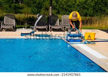 The cleaner turns on an automatic cleaning robot to clean the pool. Automatic pool cleaning. Concept photo  pool cleaning, hotel staff, service. Royalty-Free Stock Photo #2141907865