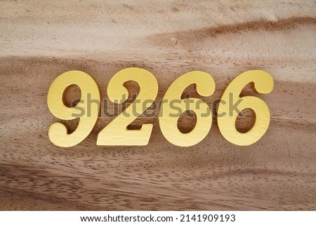 Wooden  numerals 9266 painted in gold on a dark brown and white patterned plank background.
