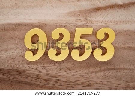 Wooden  numerals 9353 painted in gold on a dark brown and white patterned plank background.