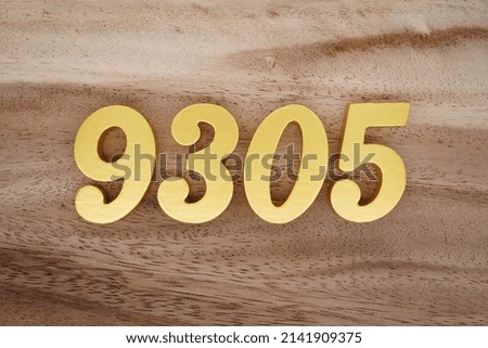 Wooden  numerals 9305 painted in gold on a dark brown and white patterned plank background.
