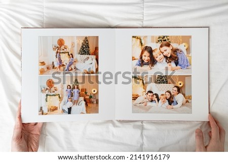 hands with a opened photobook on a white background. family photo shoot. professional printing of photos and albums in the printing, photo laboratory. photographer and designer services. memory.