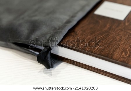 A beautiful and stylish modern wooden photo book standing on a table against a light background. photo album for memory. fabric book cover